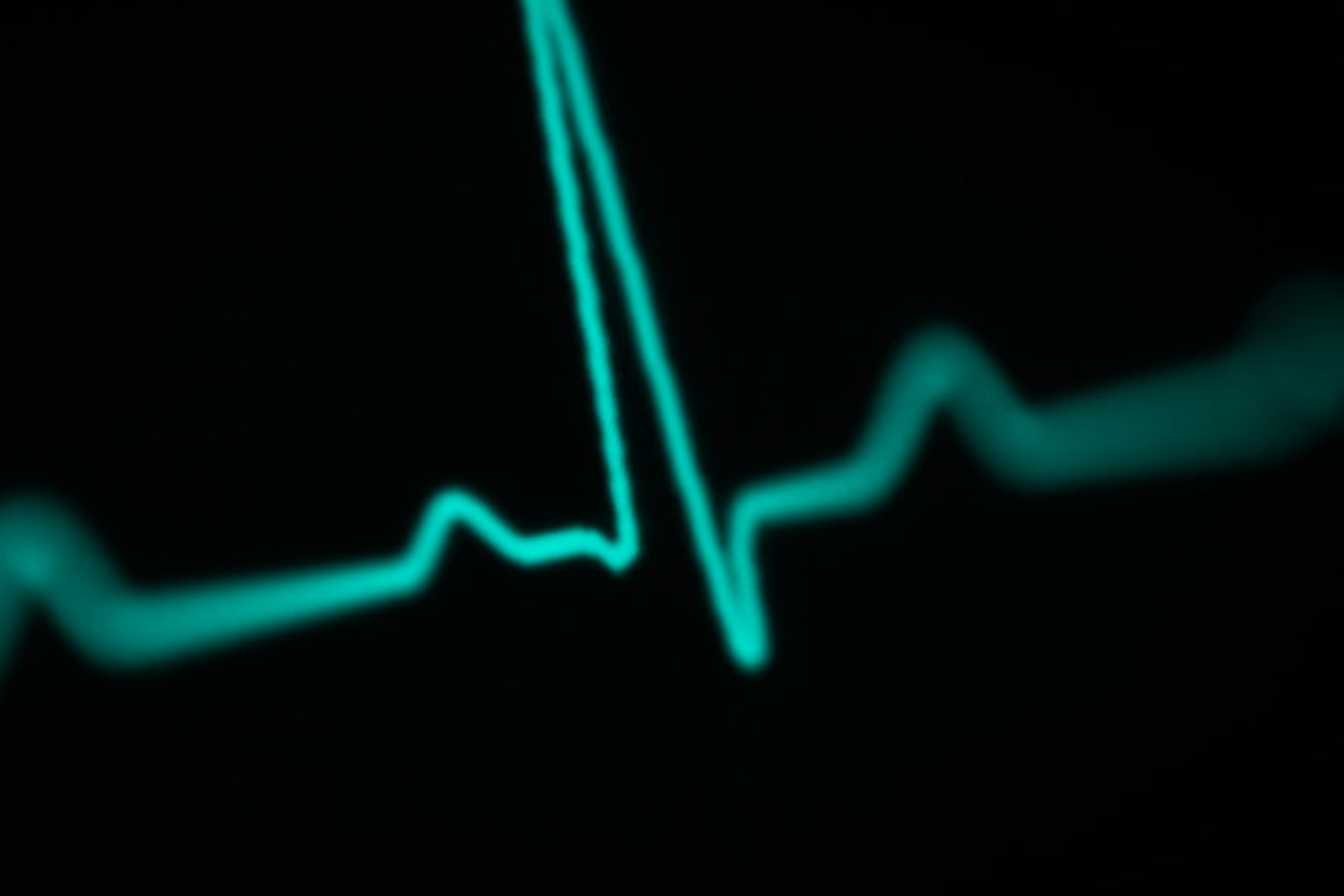 A heart-rate trace drawn in cyan light against darkness